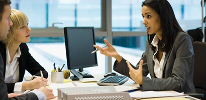People talking at a desk with a computer monitor
